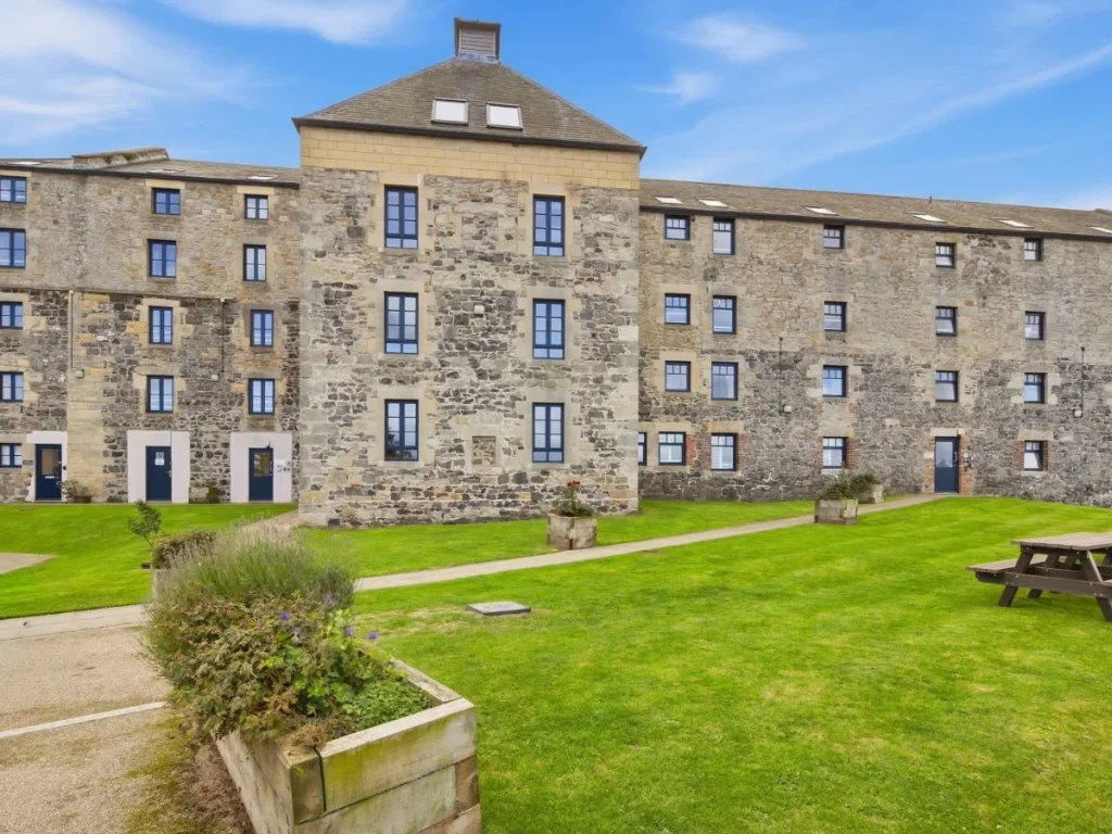 Waren Mill exterior with shared lawn, picnic seating and stone façade