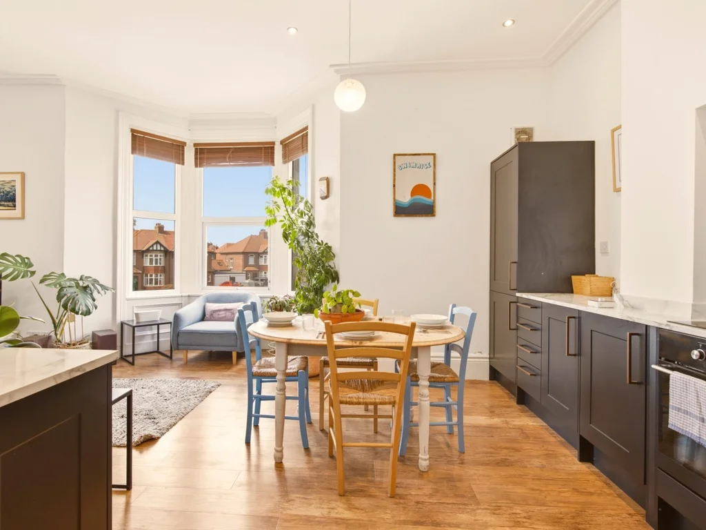 Open-plan kitchen, dining and living space with bay window outlook.