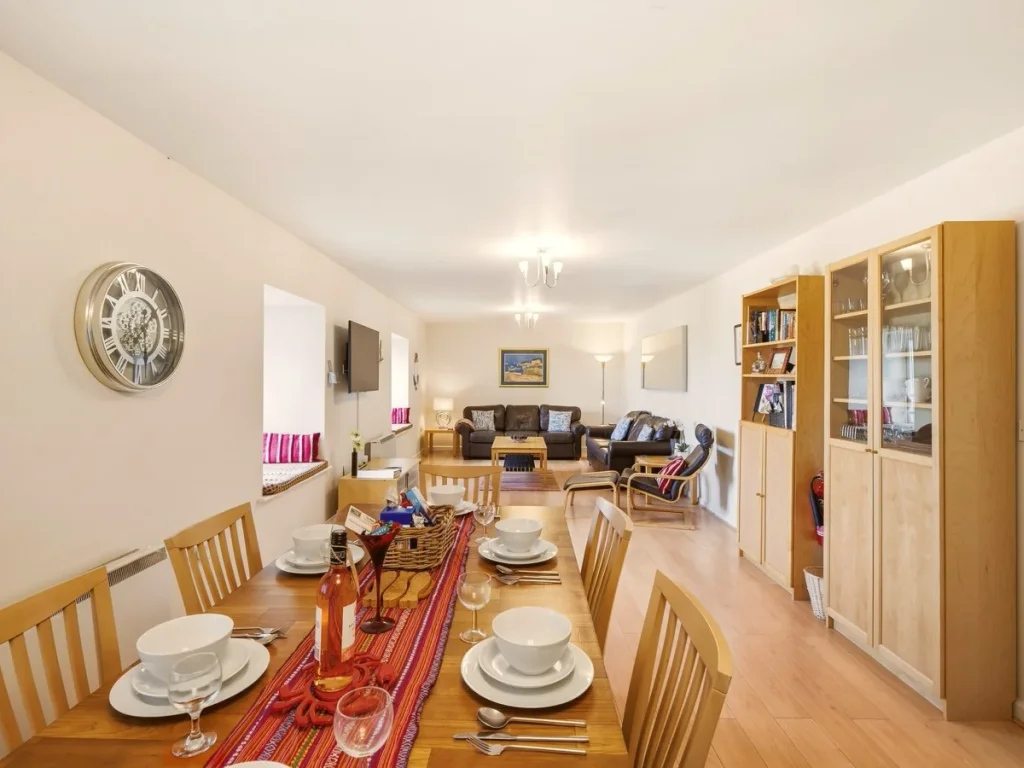 Open-plan dining and living space with wooden flooring and ample seating