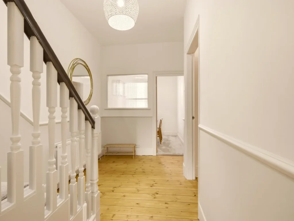 Bright first-floor landing with wooden flooring and staircase to upper floor