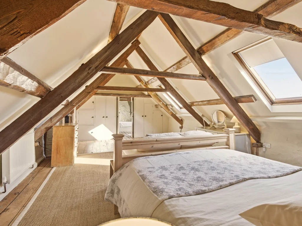 Super king bedroom with rustic beams and soft, neutral furnishings