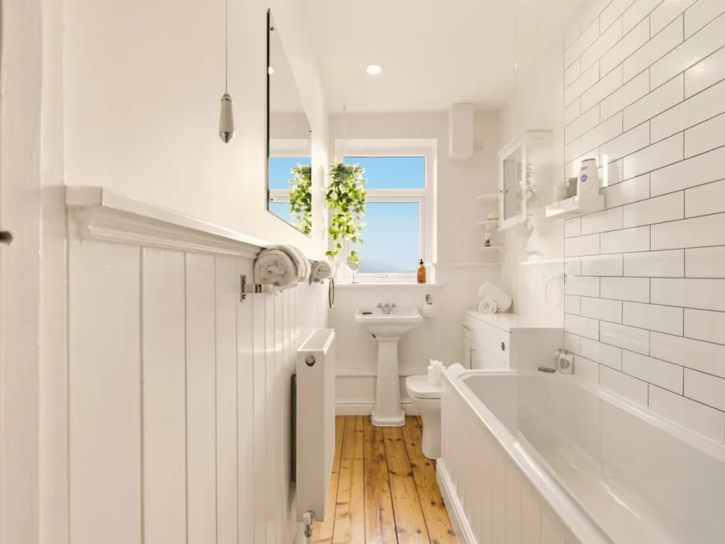 Bright family bathroom with bath, shower over, basin and wooden flooring