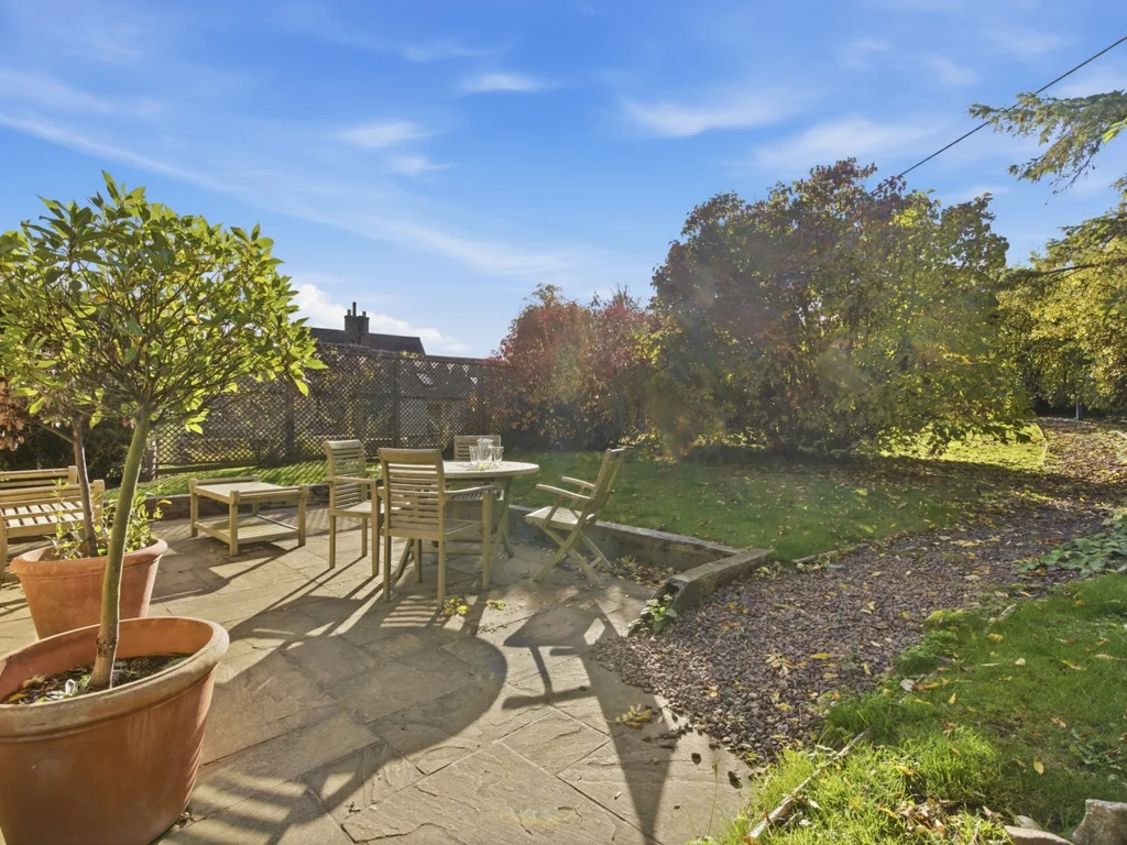 Garden patio with outdoor table and chairs surrounded by greenery