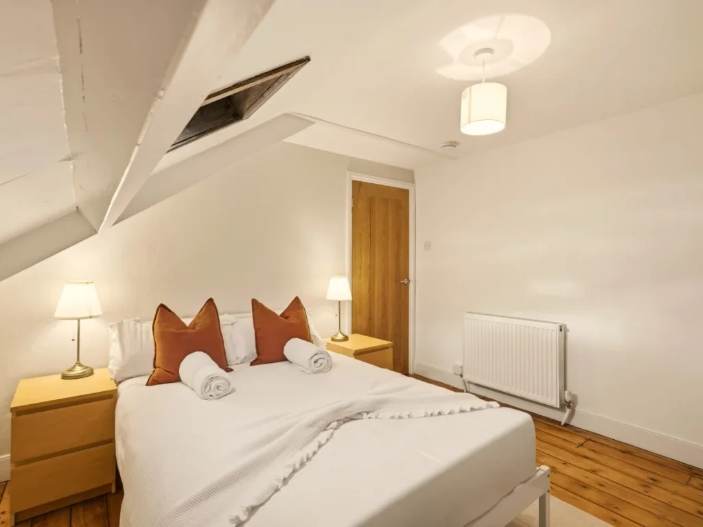 Double bedroom with bedside tables, lamps, skylight and wooden flooring
