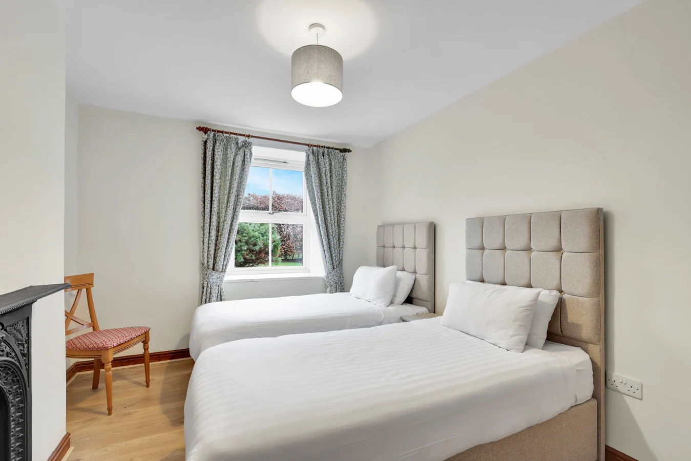 Soft neutral palette and upholstered headboards create a restful feel