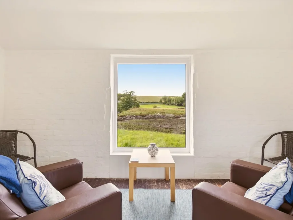 Jetty Cottage seating positioned beside a window overlooking the bay