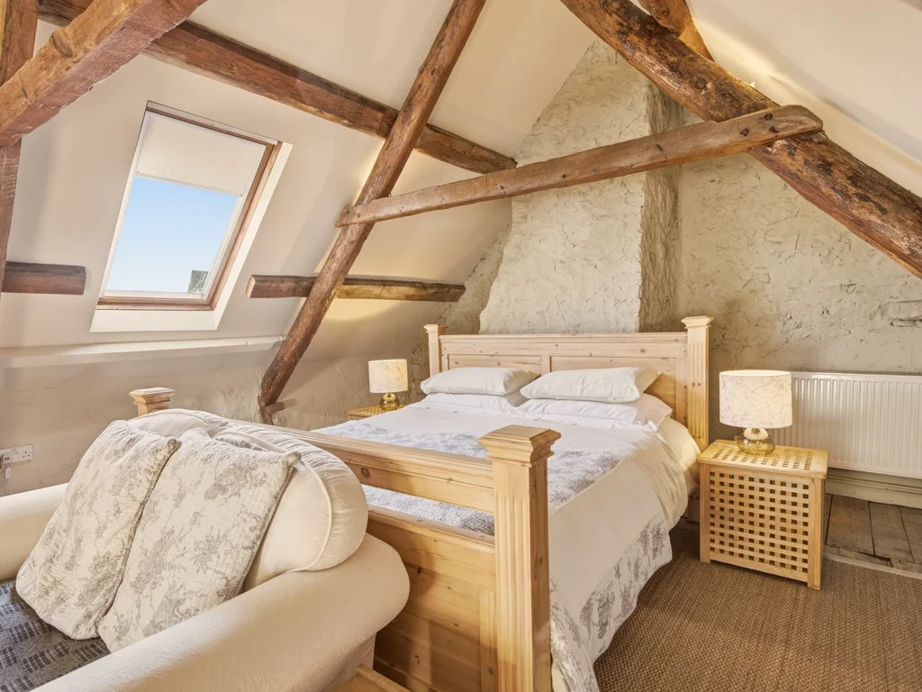 Super king bedroom with exposed beams and a cosy seating area