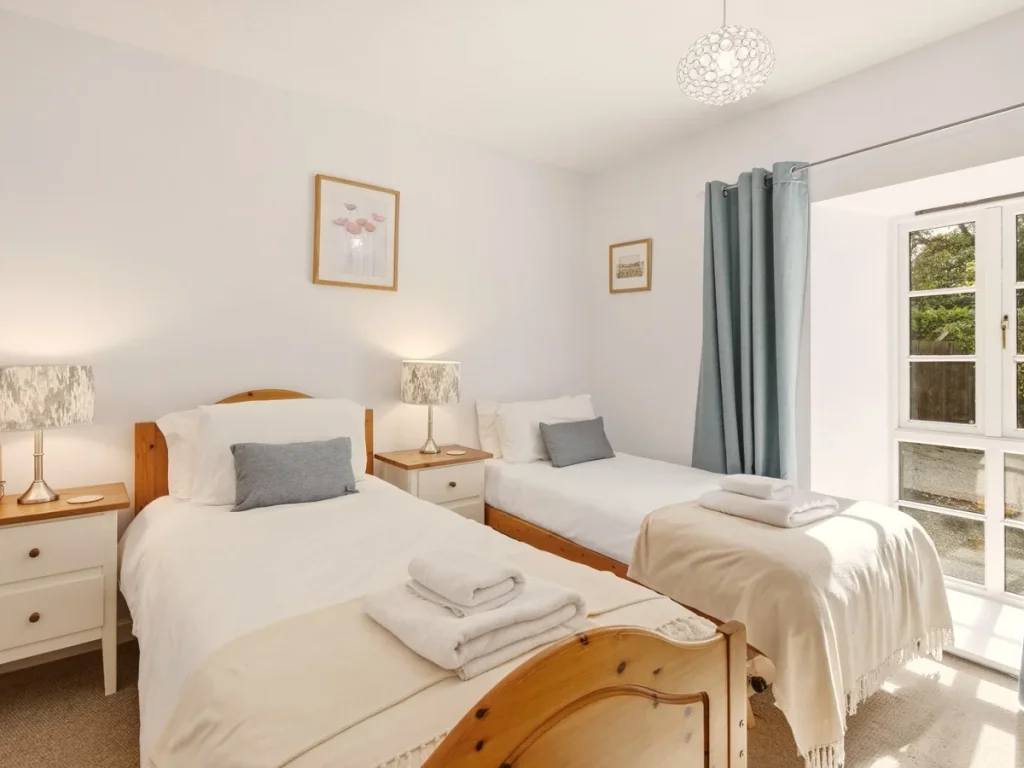 Twin bedroom with two single beds, bedside storage and garden outlook