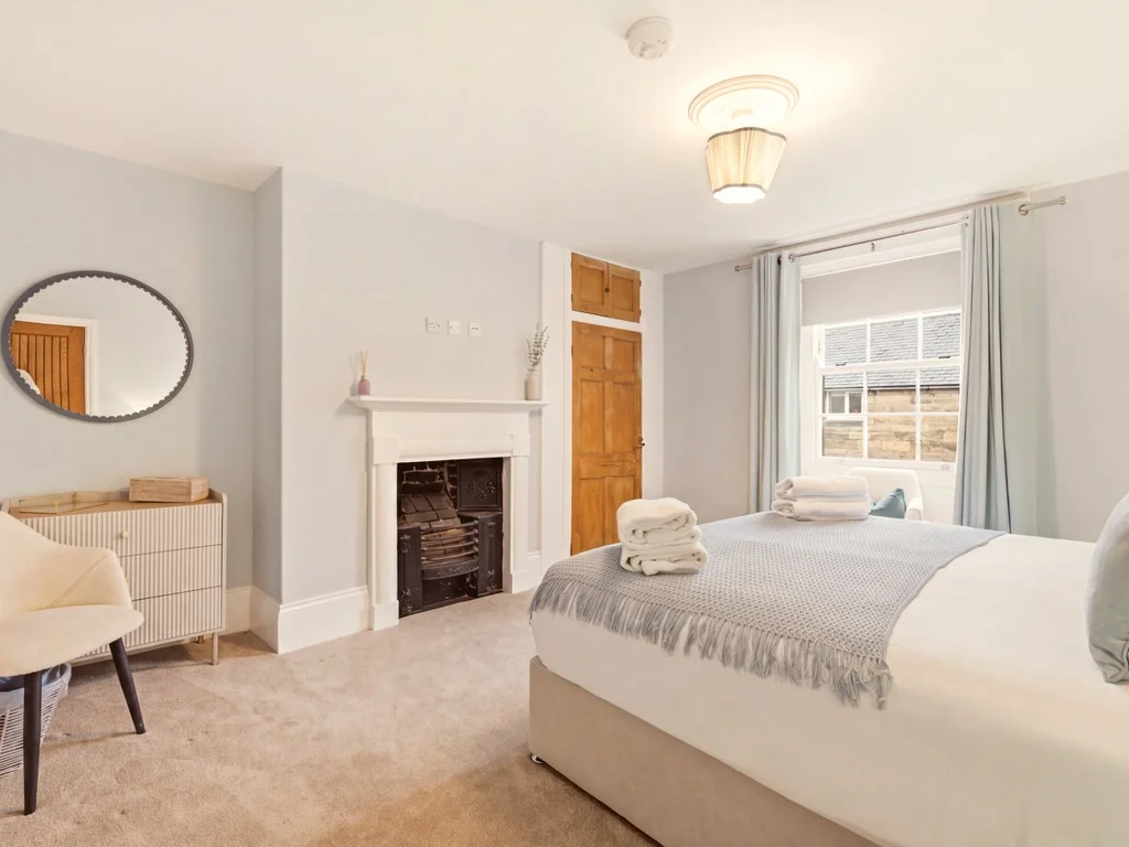 Spacious King Zip bedroom with feature fireplace, dressing area and village views.