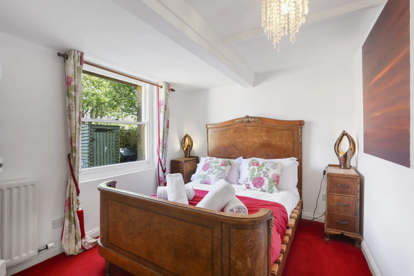 Double bedroom with wooden bed frame and red carpet