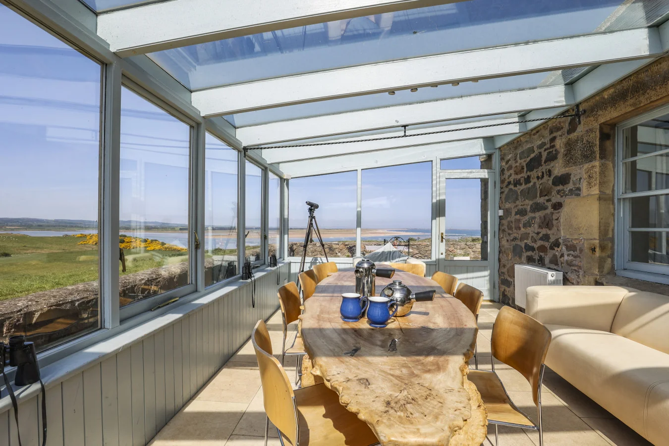 Conservatory with dining table, seating, and Budle Bay views