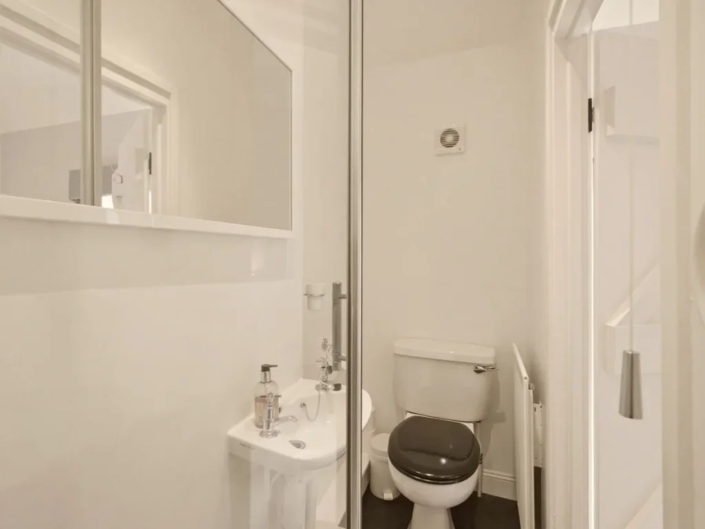 Bright en-suite shower room with electric shower, WC and compact wash basin