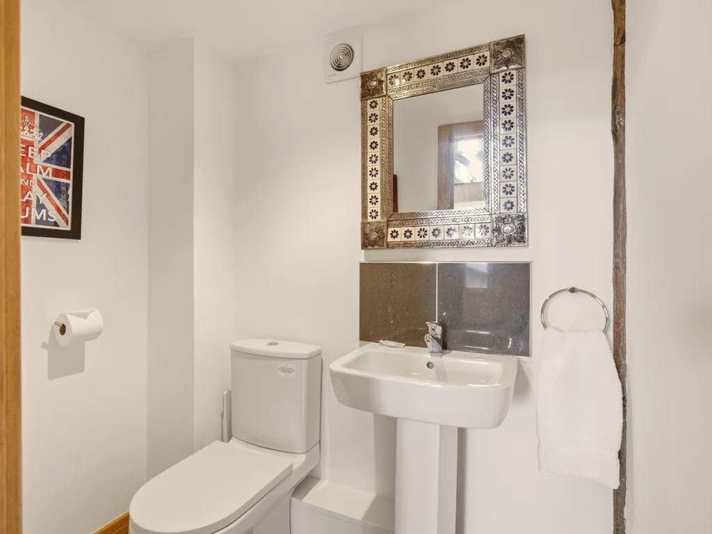 Private en-suite with WC, pedestal wash basin and decorative mirror