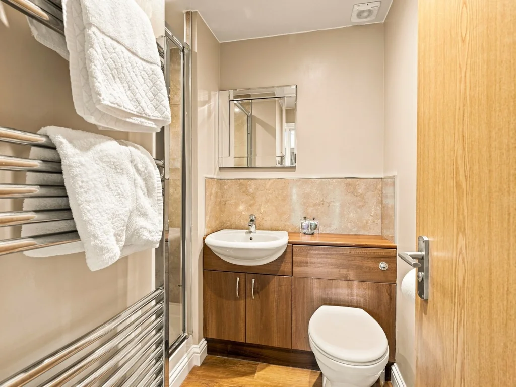 En-suite shower room with vanity unit, heated towel rail and mirror.