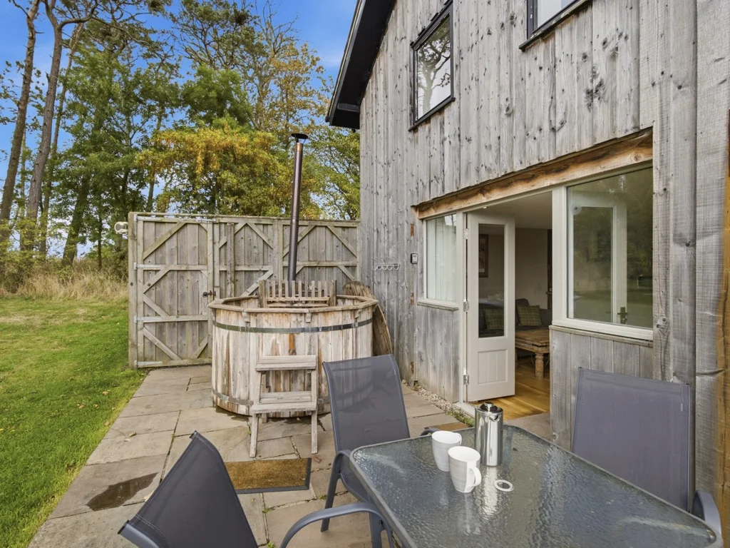 Patio dining area with wood-fired hot tub beside Drum Barn