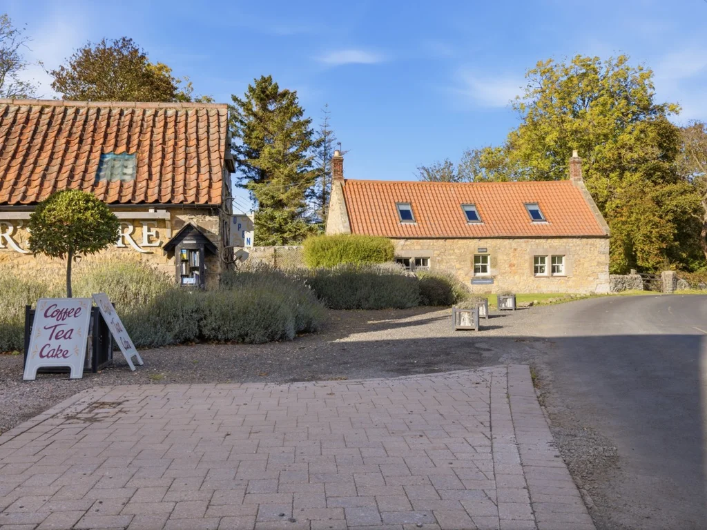 Stone-built cottage and entrance beside the village road