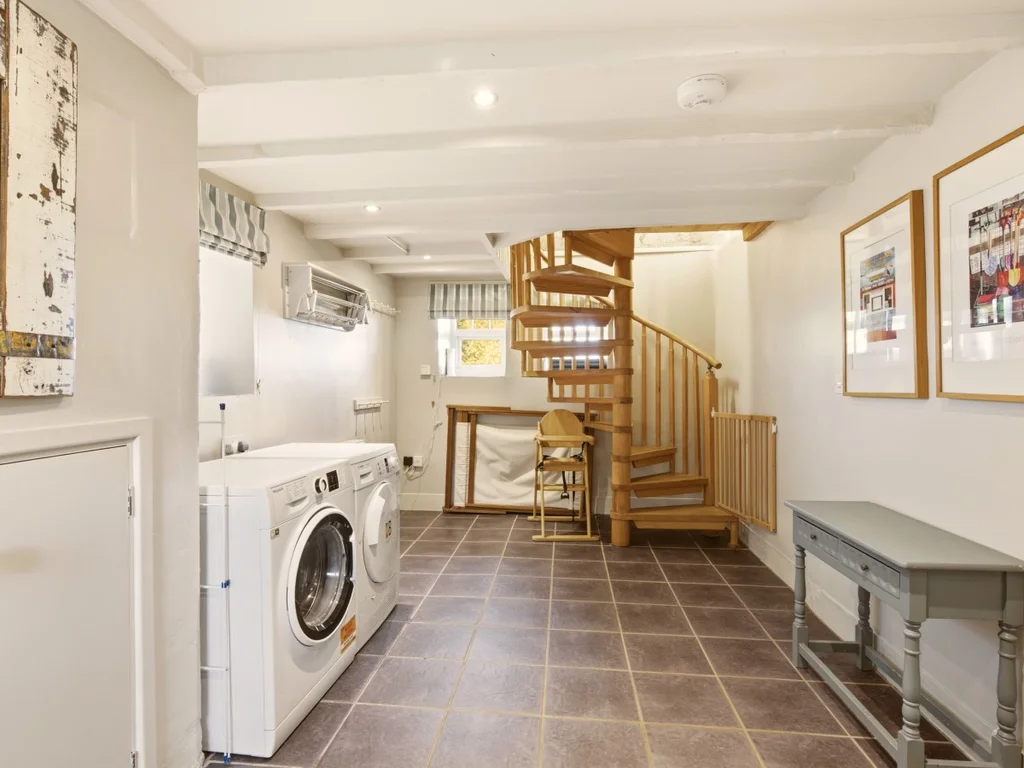 Utility room with laundry appliances and a wooden staircase