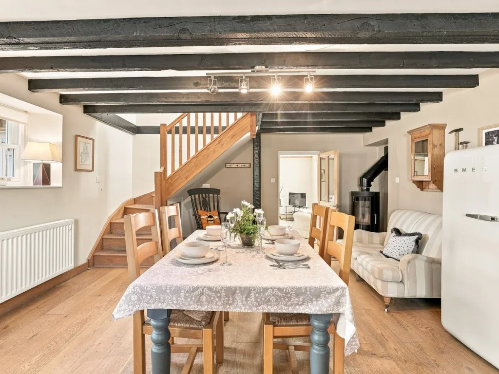 Dining area with exposed beams, wooden staircase and table setting