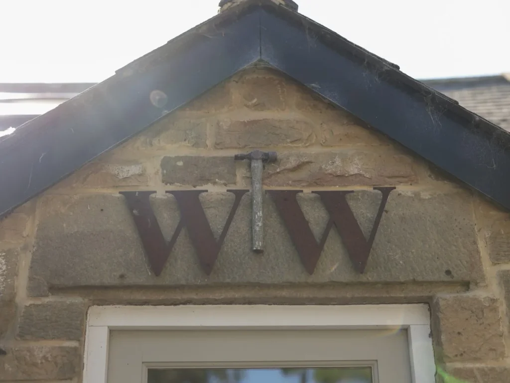 Stone entrance gable with WW initials marking Woodworkers Cottage