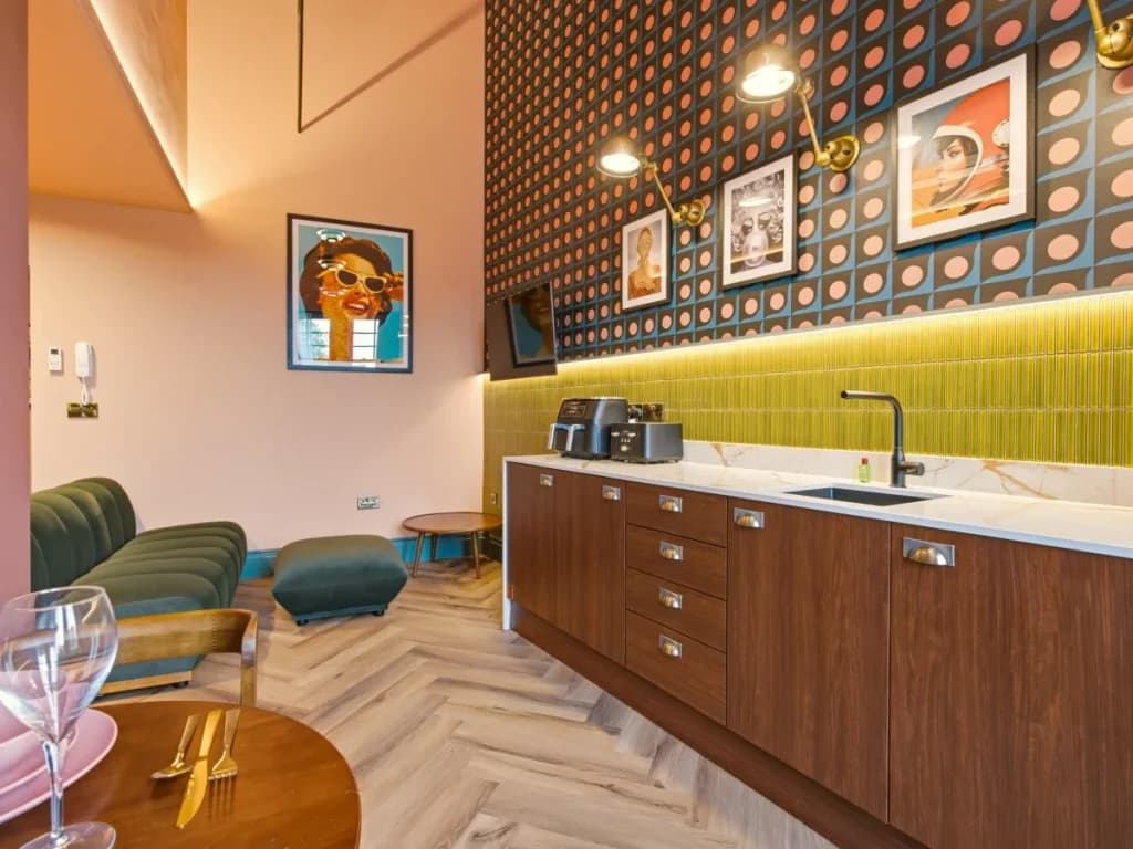Kitchenette with green tiled splashback, dining table and lounge seating
