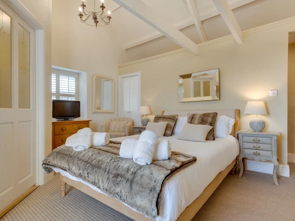 Spacious king bedroom with characterful exposed beams and elegant furnishings.