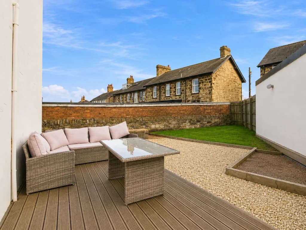 Enclosed rear garden with seating on decking area.