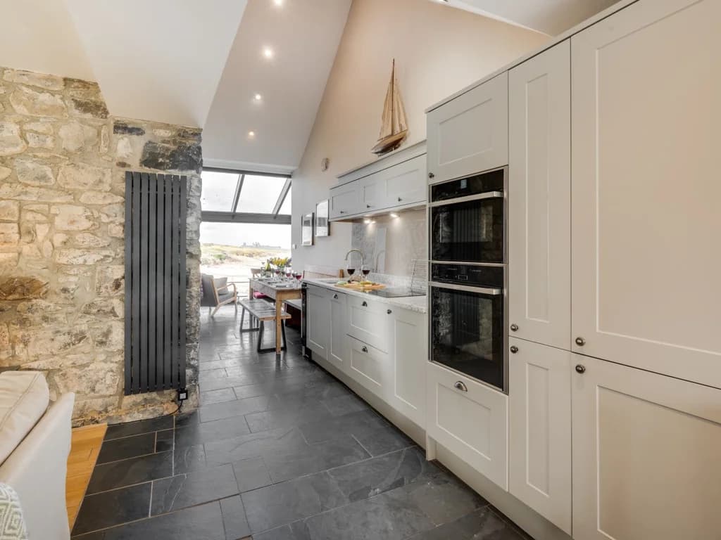 Stylish, fully equipped kitchen blending contemporary finishes with characterful exposed stone walls.