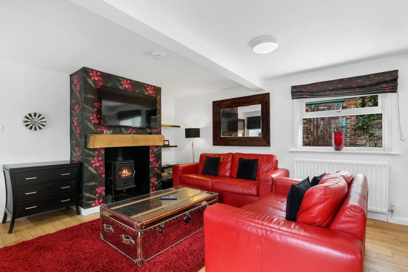 Lounge with red leather sofas, log burner and floral fireplace
