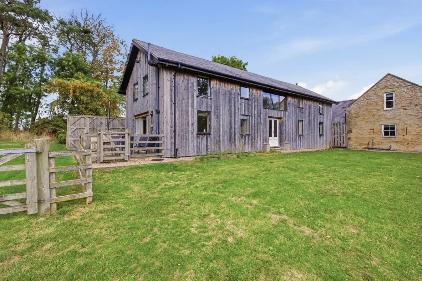 Timber-clad Drum Barn surrounded by open lawns and countryside