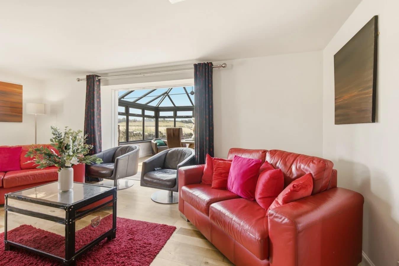 Living room with red sofas opening into the glass-roof conservatory