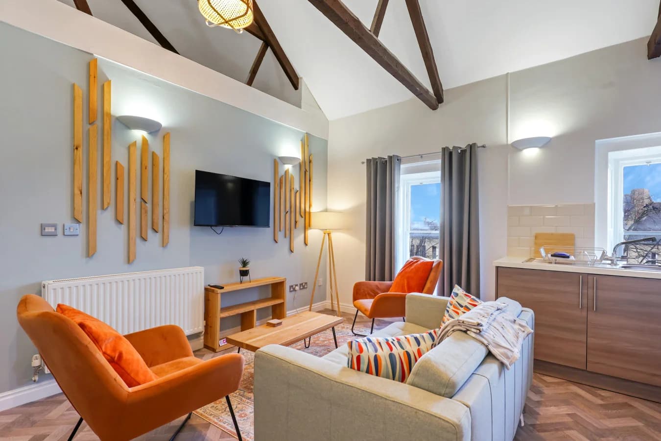 Open-plan living area with vaulted ceilings, exposed beams and warm orange accents