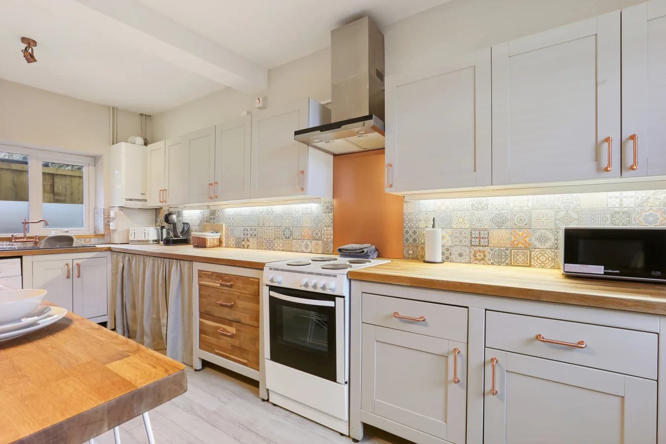 Well-equipped kitchen with patterned splashback and warm timber accents