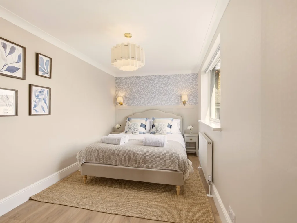 Double bedroom with grey upholstered bed and feature wallpaper