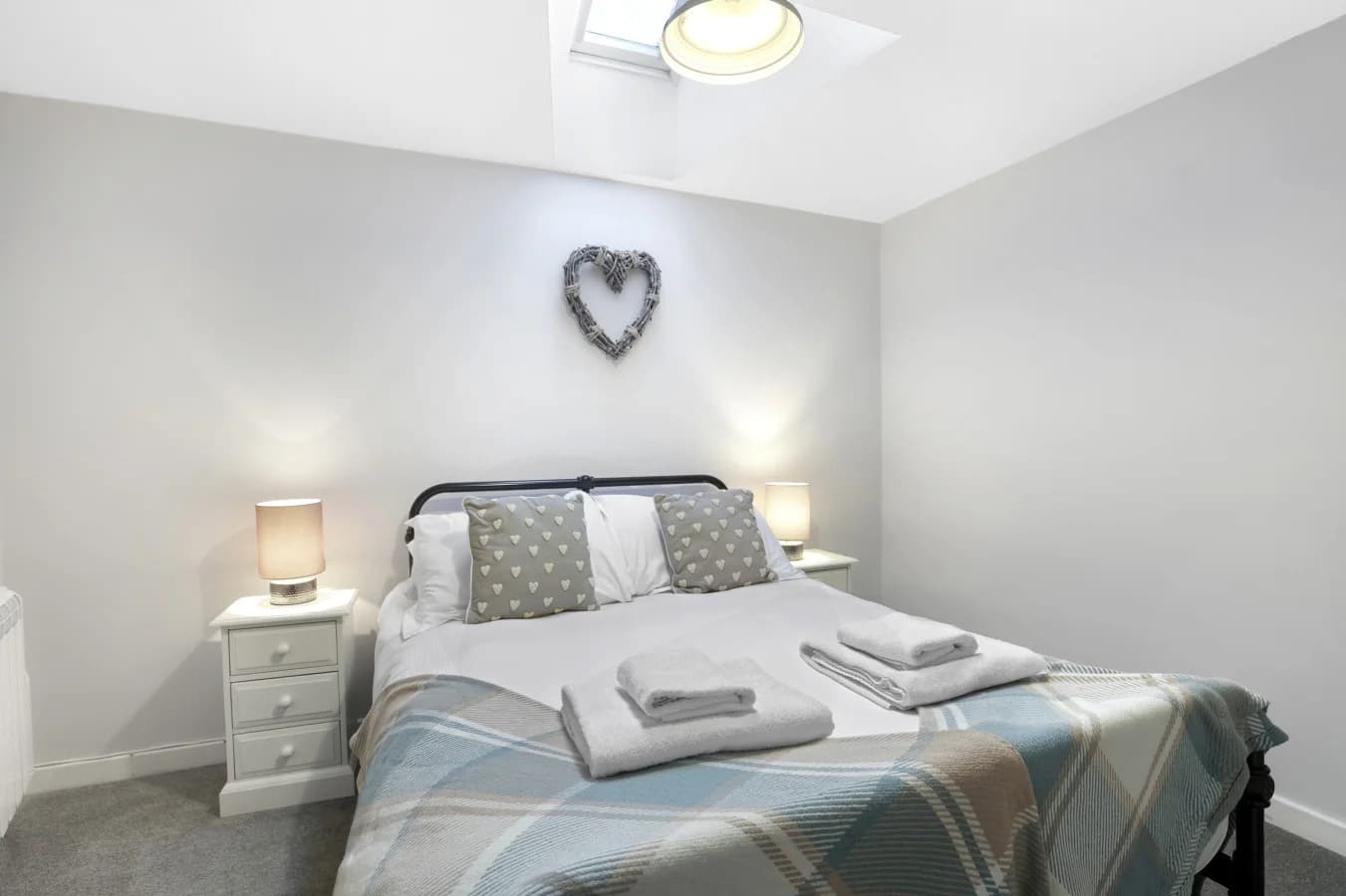 King bedroom with soft grey tones, skylight and heart wall feature