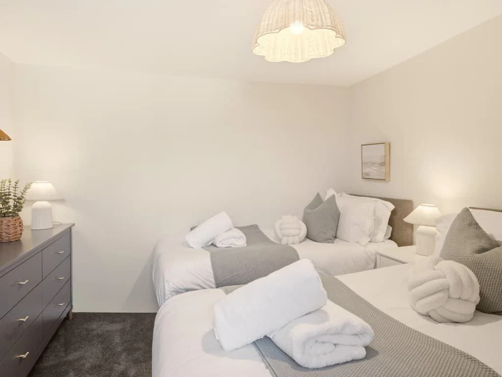 Twin bedroom with matching beds, bedside lamps and chest of drawers.