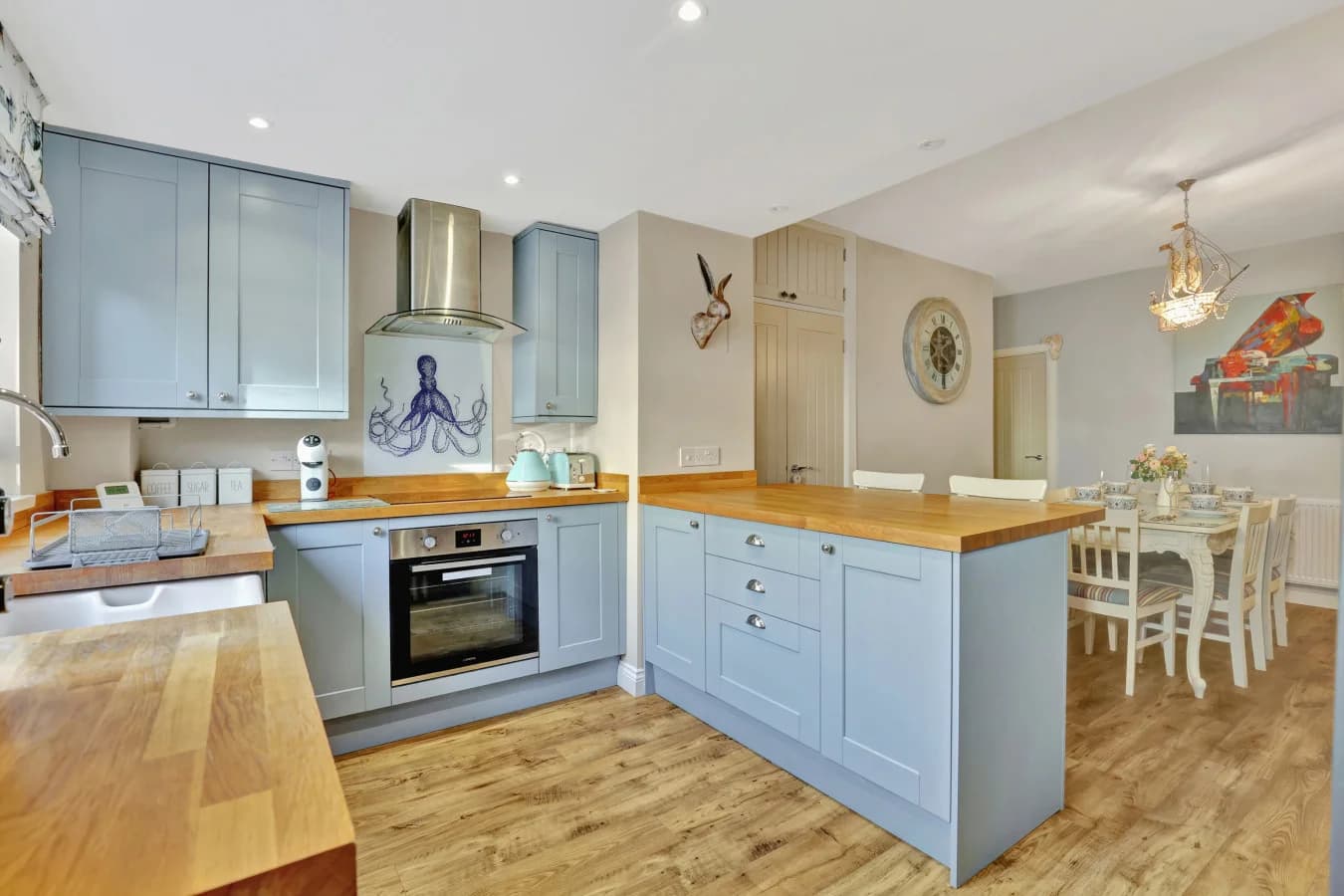 Open-plan kitchen with blue cabinetry, oak worktops and breakfast bar