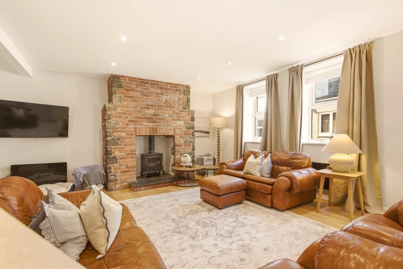 Living room with leather sofas, exposed brick fireplace and wood burner.