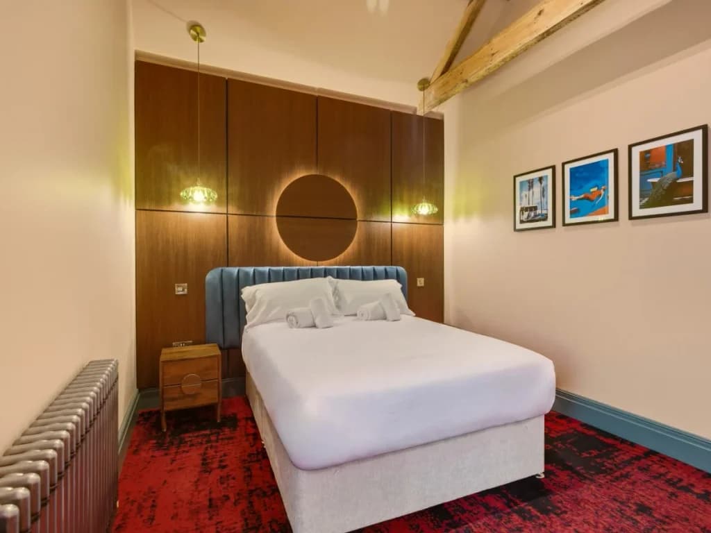 Double bedroom with wood-panelled feature wall and colourful artwork