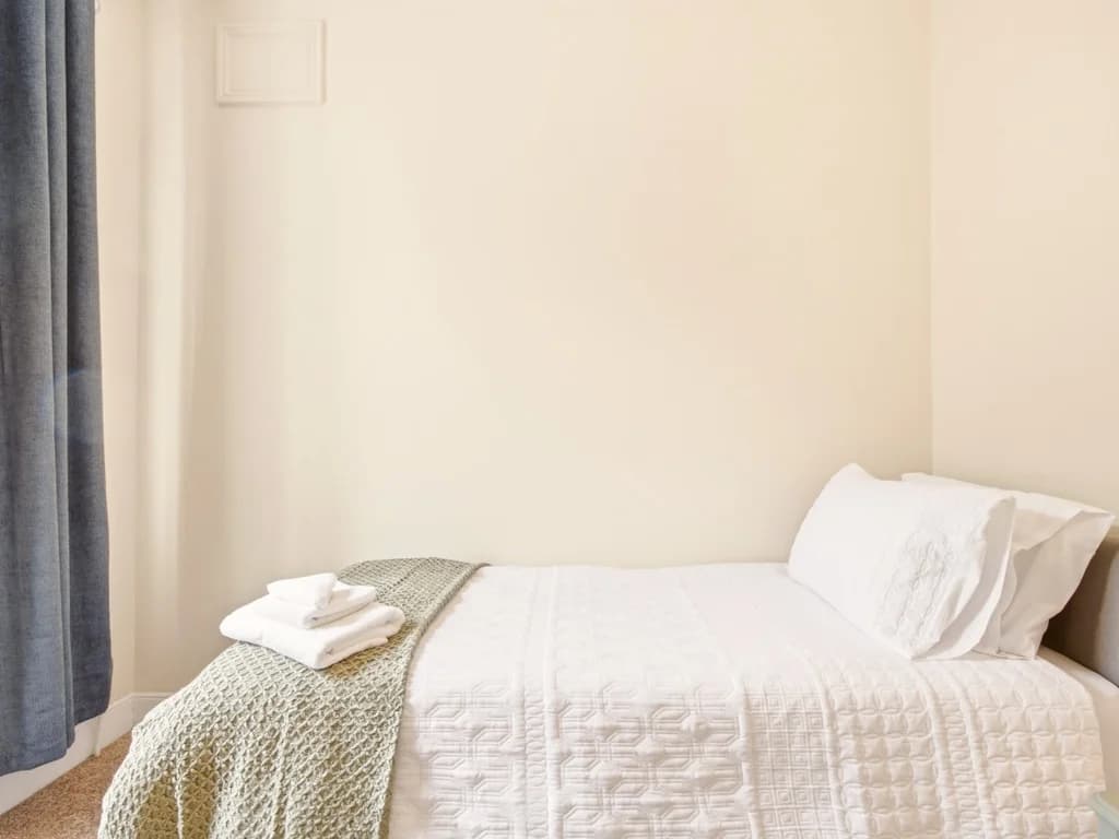 Single bedroom with bedside table and colourful dog artwork.