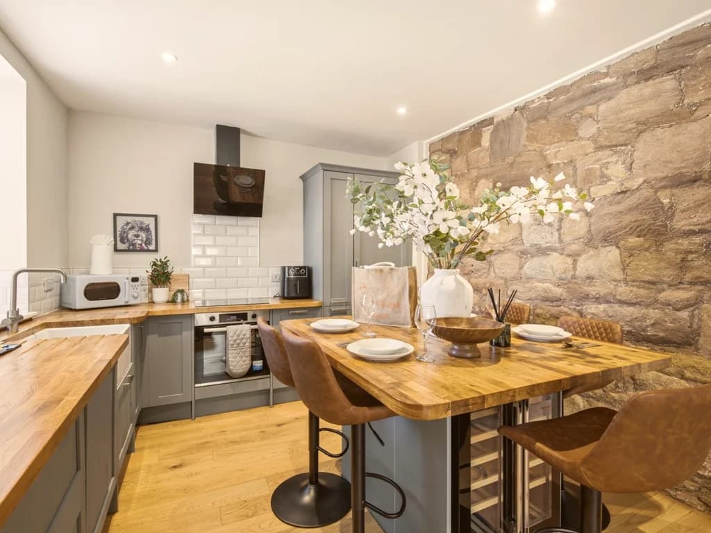 Kitchen and dining area with stone feature wall and breakfast bar.