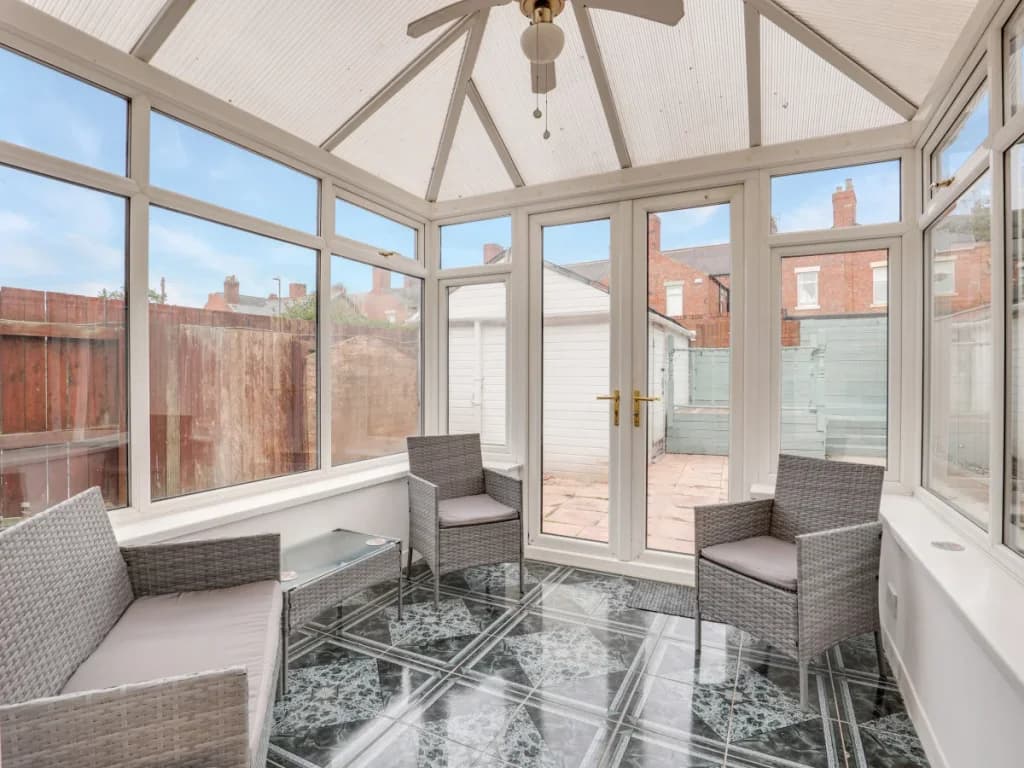 Bright conservatory with garden seating and doors opening to the patio