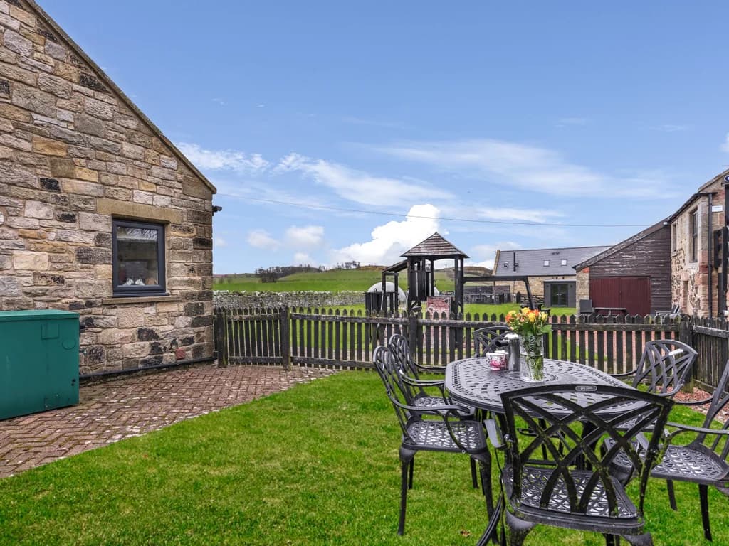 Enclosed garden with outdoor dining area and shared play space beyond