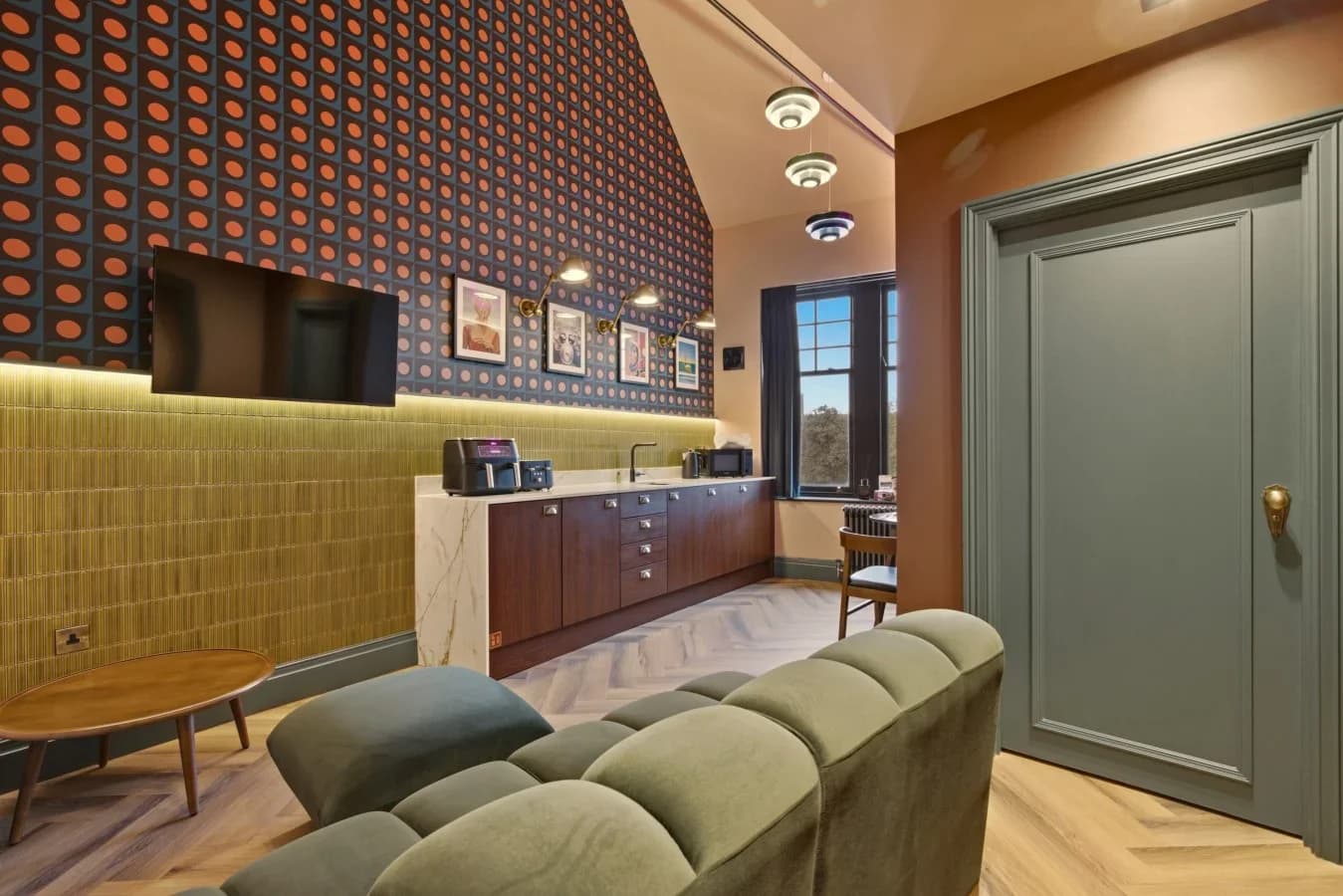 Open-plan living area with patterned feature wall and compact kitchenette