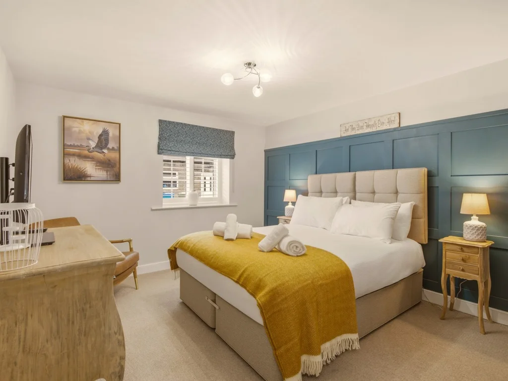 Spacious zip-link king bedroom with feature wall and oak bedside furniture