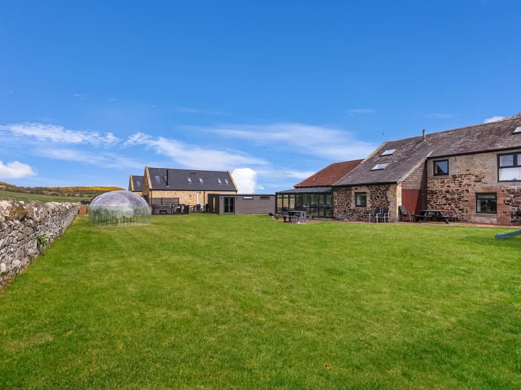 Large shared grass paddock with stone cottages and garden domes.