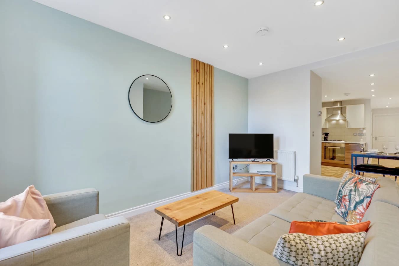 Spacious lounge with pale green walls, natural wood finishes and Smart TV