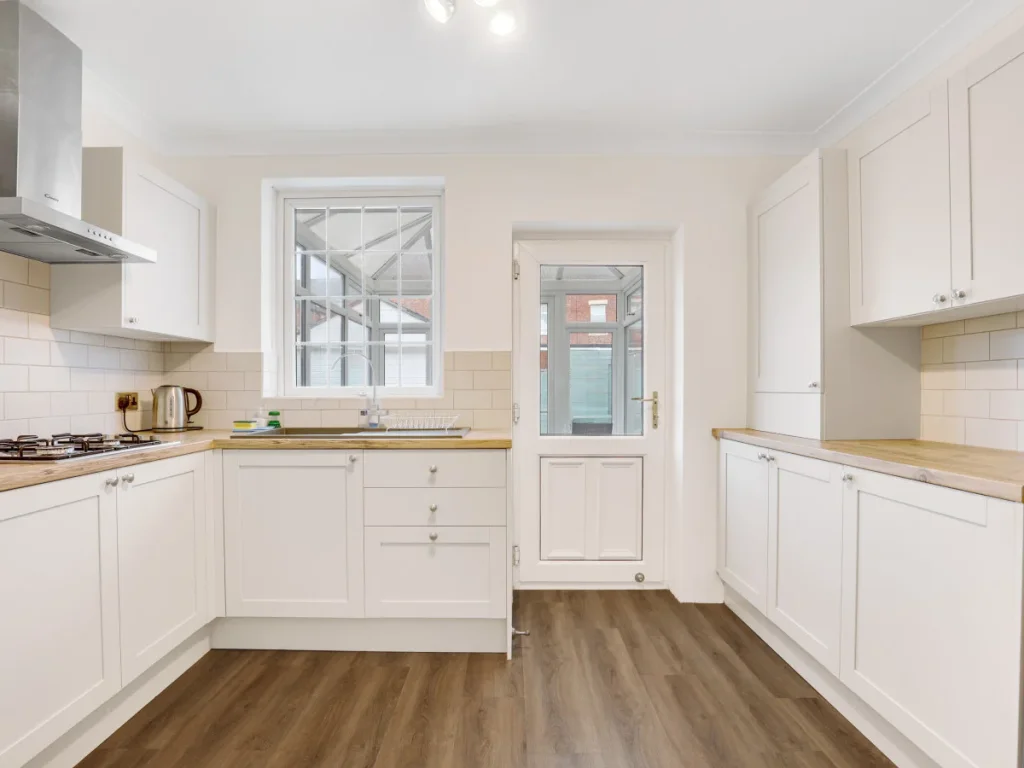 White fitted kitchen with wood worktops, gas hob and ample storage