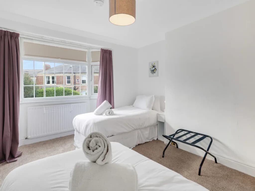 Twin bedroom with two single beds, large window and luggage rack