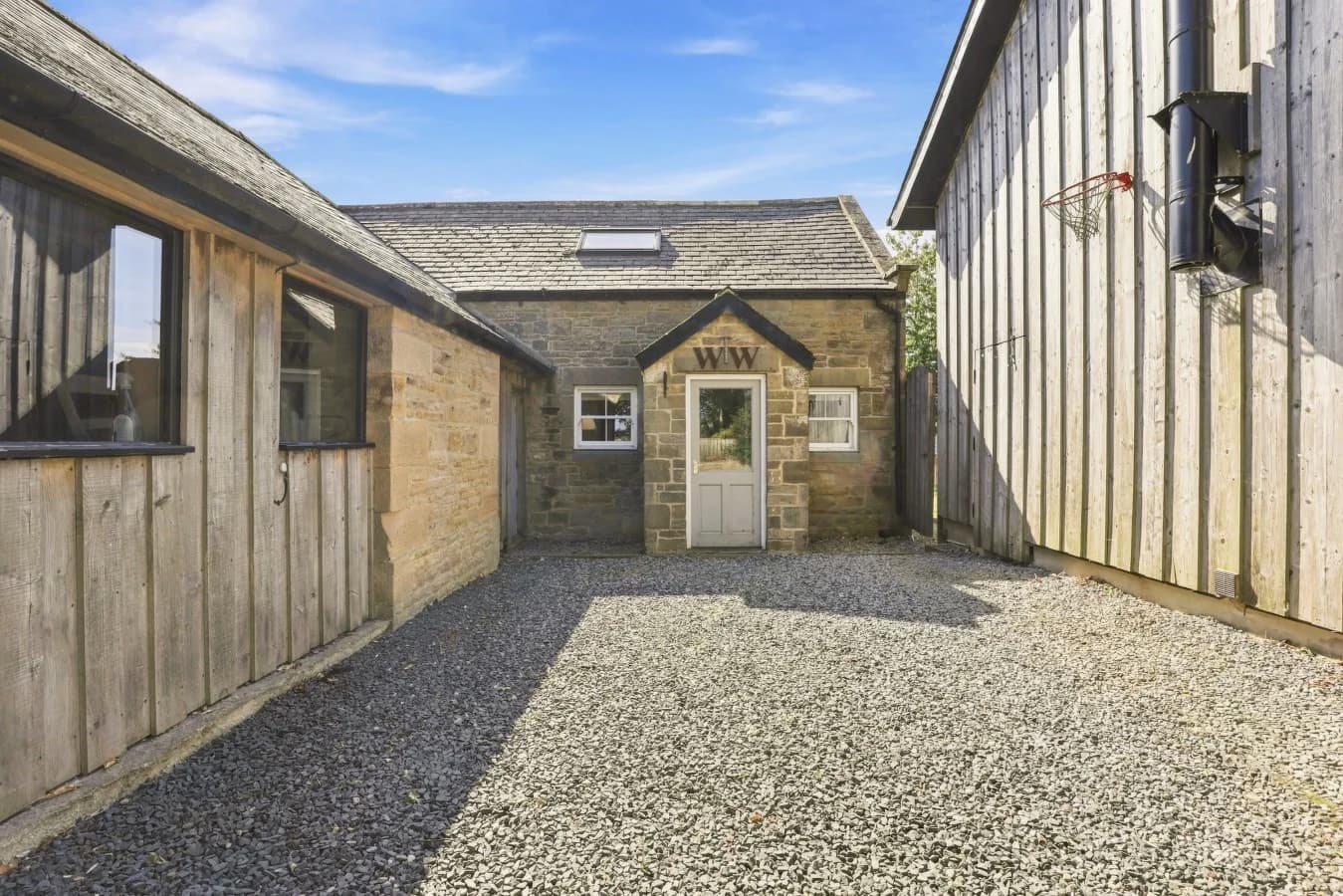Stone cottage entrance with gravel courtyard and timber cladding