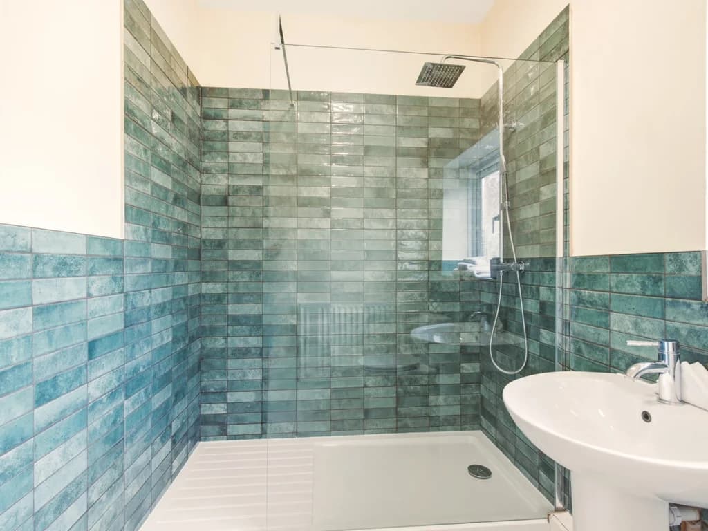 Bathroom with walk-in shower and blue glazed wall tiles.